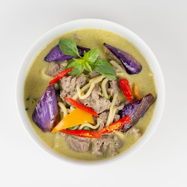 Green curry with beef, purple eggplant, bamboo shoots, red and yellow bell peppers, and basil.