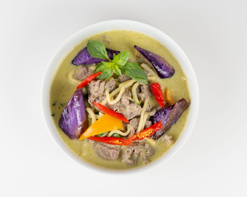 Green curry with beef, purple eggplant, bamboo shoots, red and yellow bell peppers, and basil.